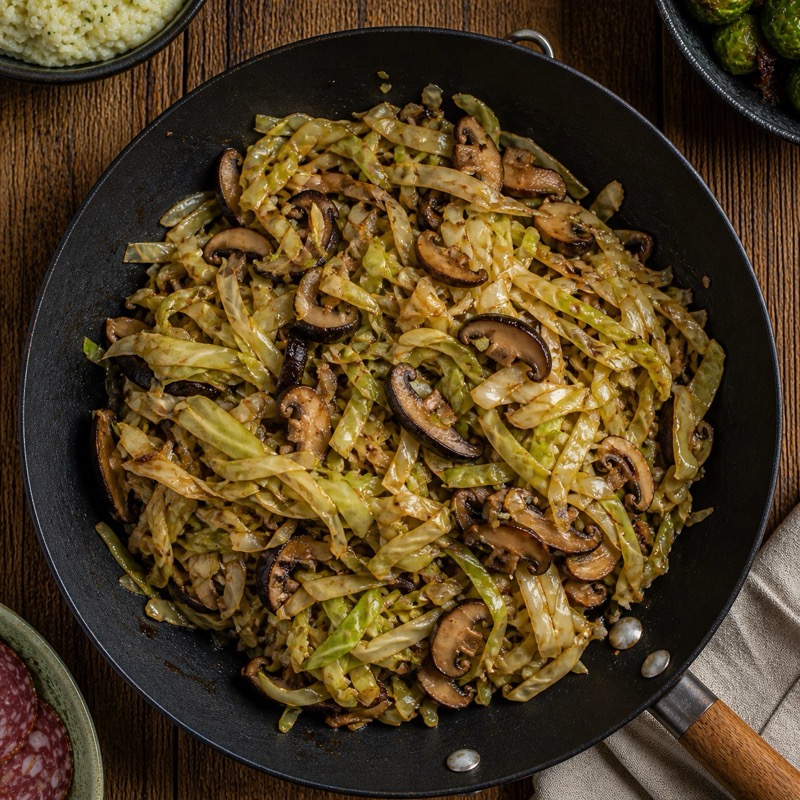 Roergebakken spitskool met shiitake en champignons in een wok